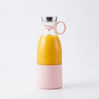 A portable electric juicer bottle filled with a vibrant mango smoothie against a clean white background.